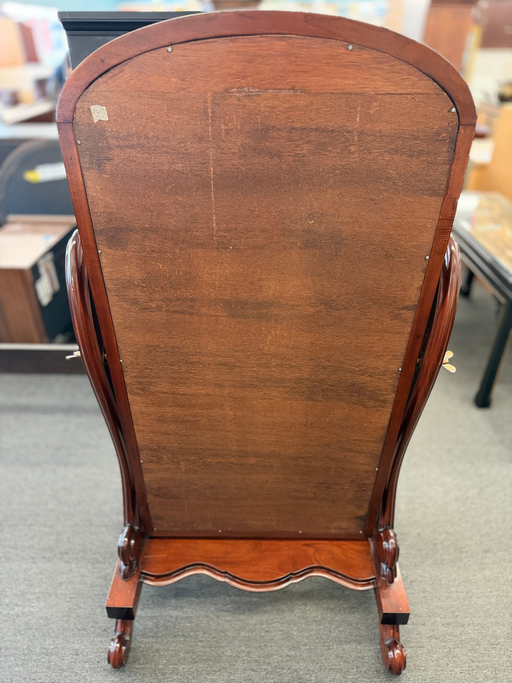 Traditional freestanding oval cheval mirror with a polished wood frame, adjustable full-length mirror, decorative scrolled legs, and a sturdy wooden base.