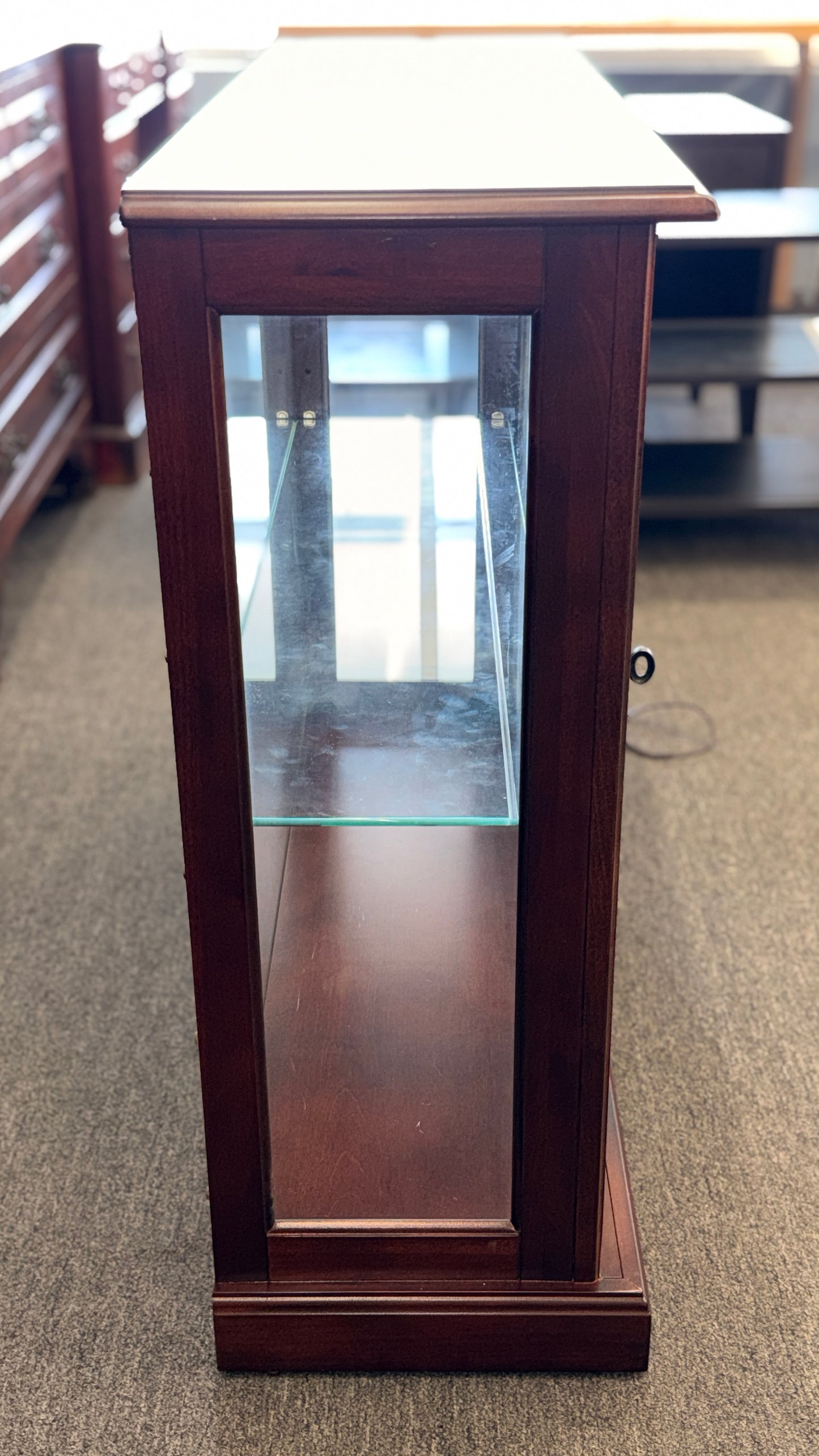 A traditional wooden display cabinet featuring glass doors, glass side panels, interior glass shelving, and a reddish-brown finish.