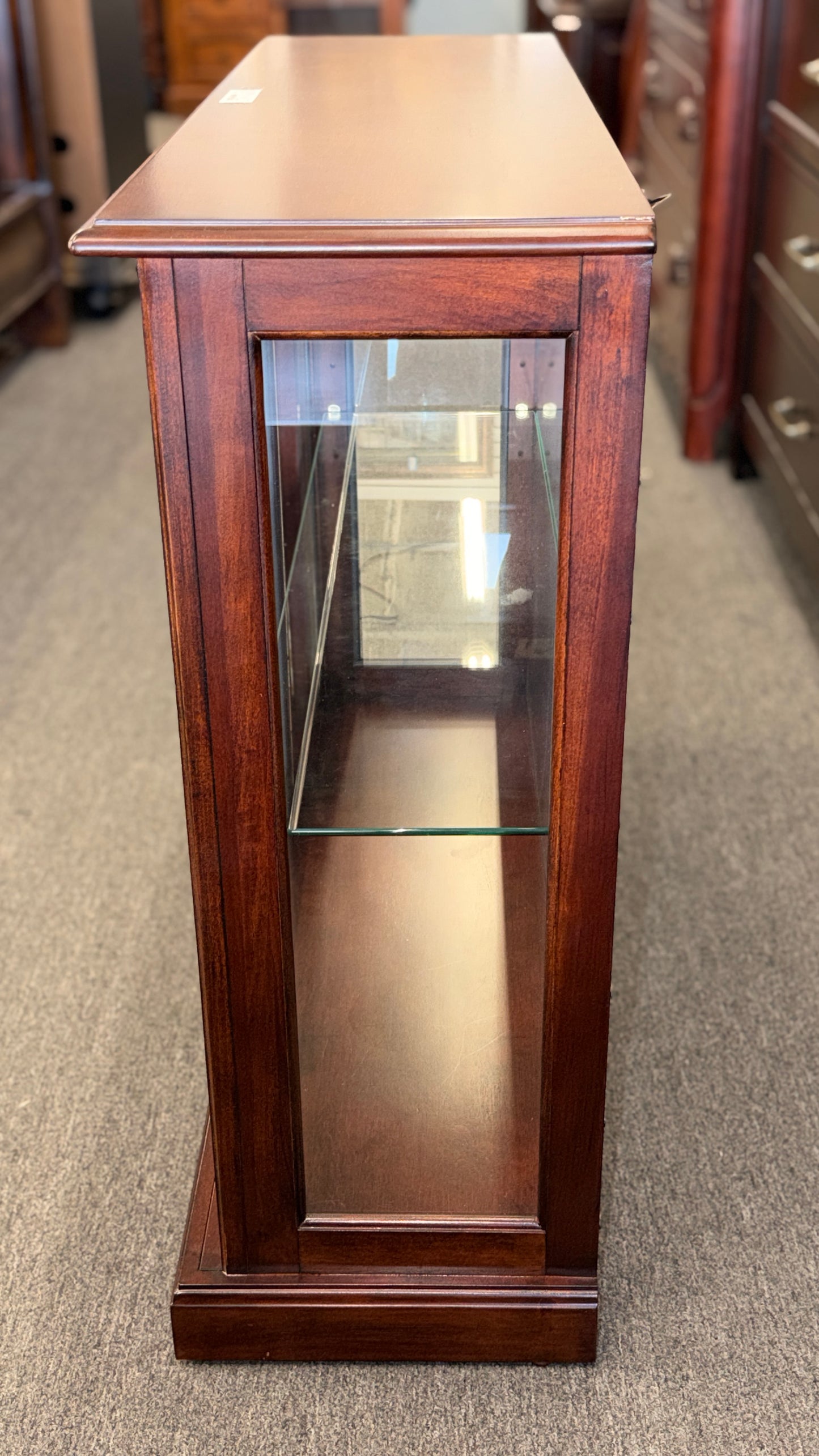 A traditional wooden display cabinet featuring glass doors, glass side panels, interior glass shelving, and a reddish-brown finish.