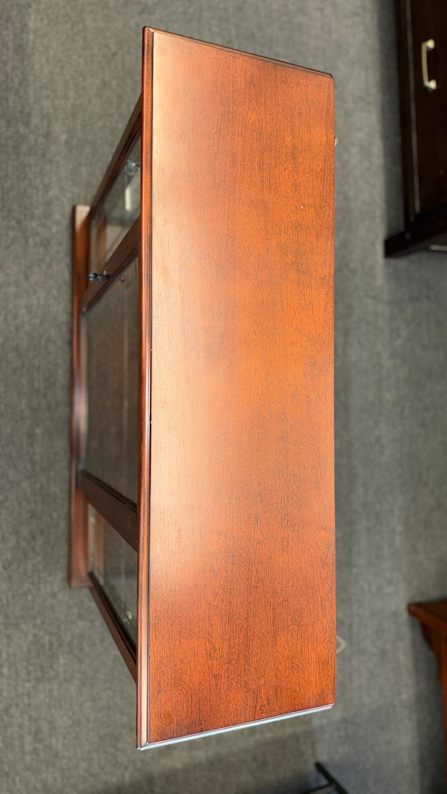 A traditional wooden display cabinet featuring glass doors, glass side panels, interior glass shelving, and a reddish-brown finish.