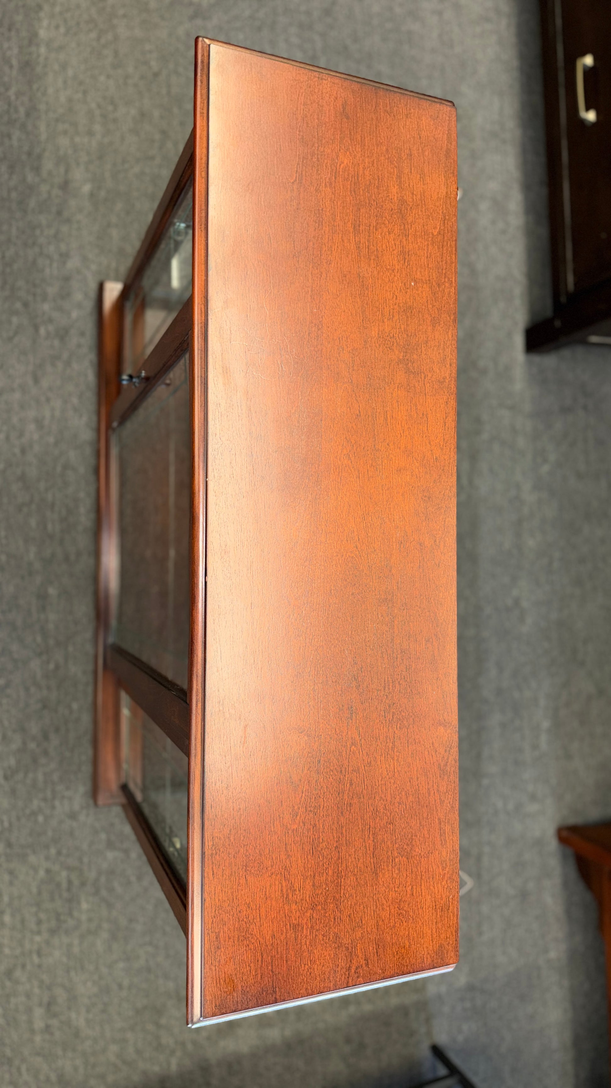 A traditional wooden display cabinet featuring glass doors, glass side panels, interior glass shelving, and a reddish-brown finish.