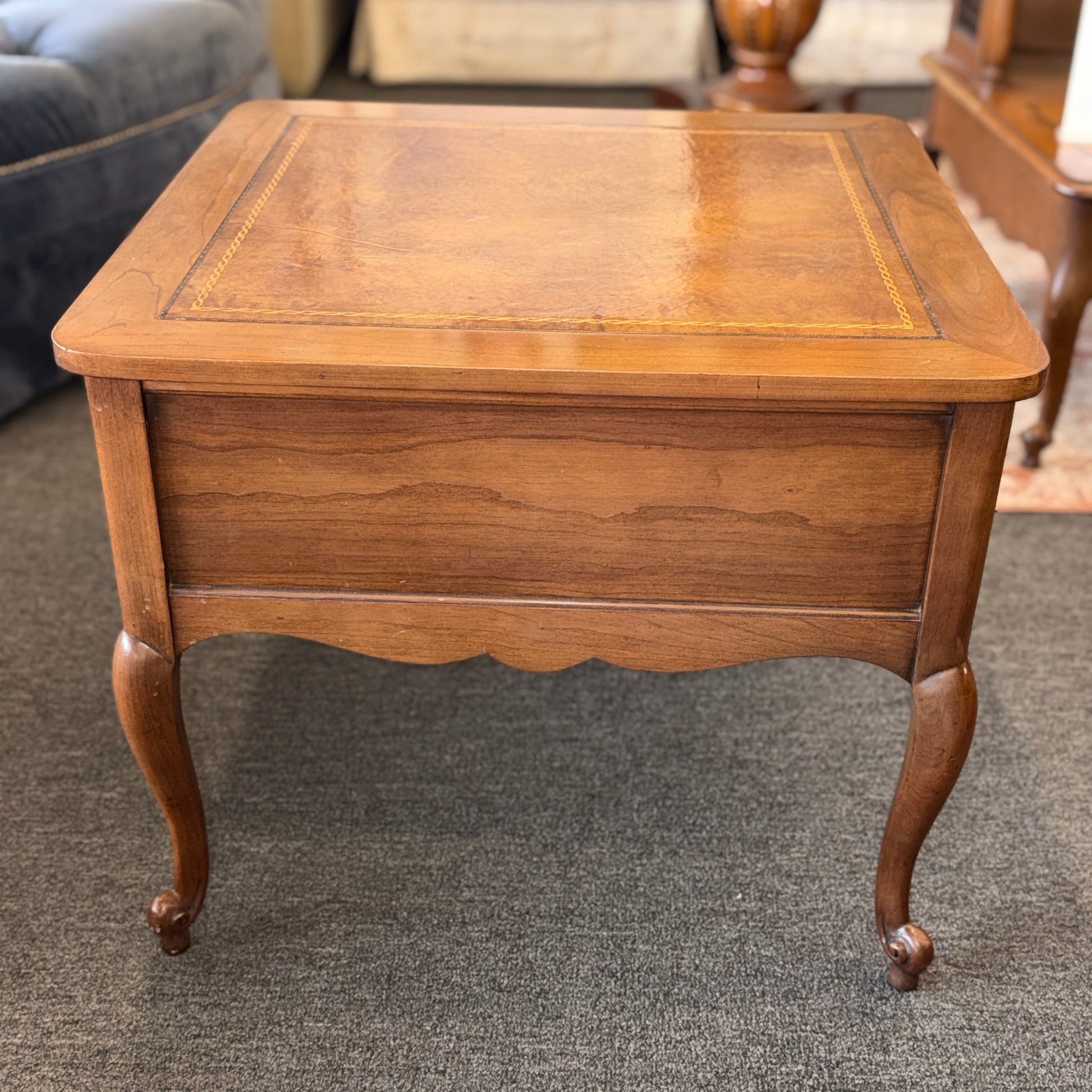 A square wooden end table featuring decorative gold inlay, two stacked drawers with ornate ring pulls, and cabriole legs.