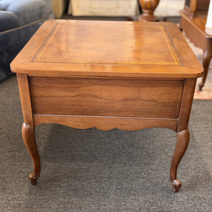 A square wooden end table featuring decorative gold inlay, two stacked drawers with ornate ring pulls, and cabriole legs.