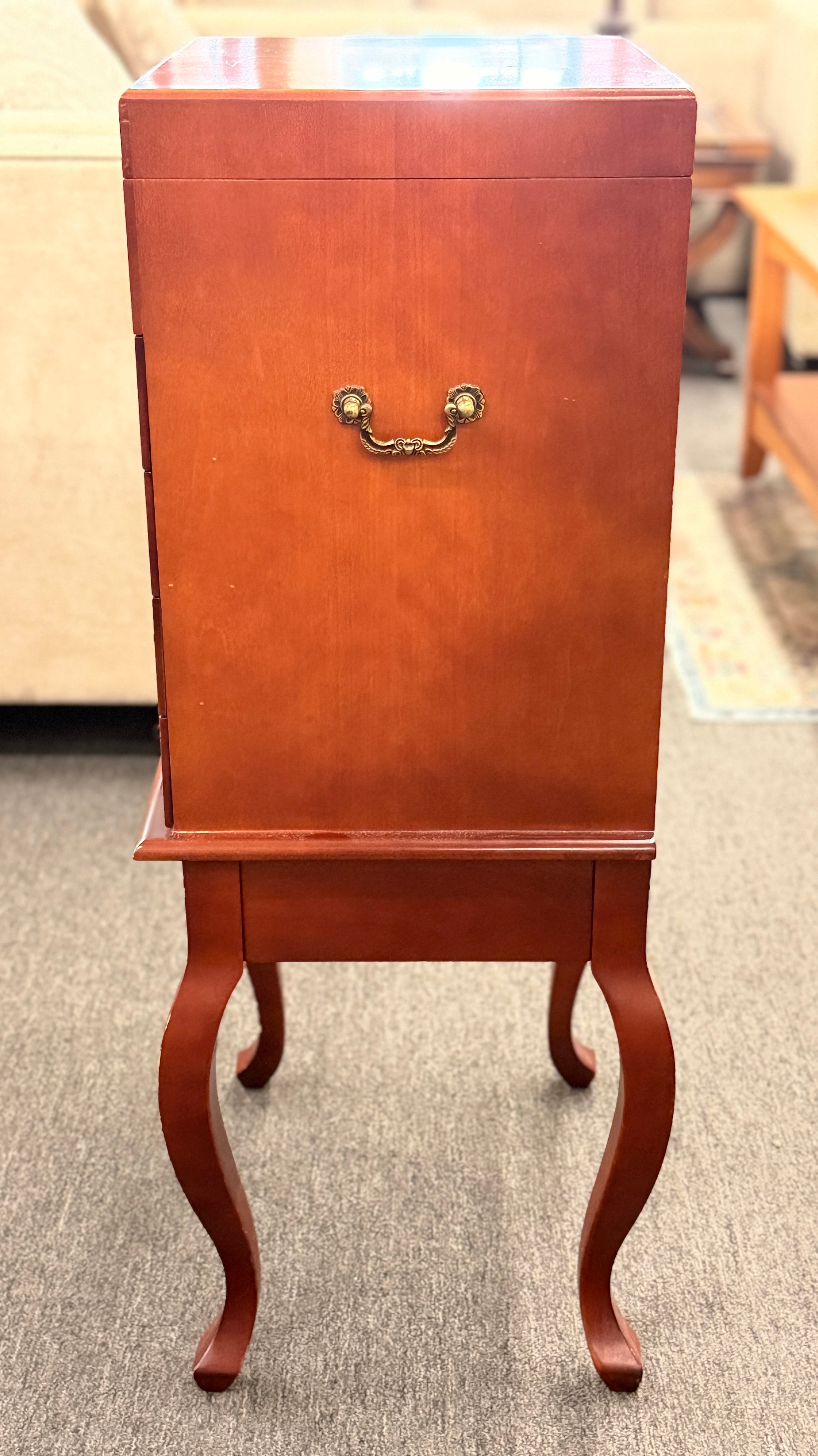A tall, upright wooden jewelry or silverware chest shown open, revealing a ring-roll top compartment, five stacked drawers, burgundy fabric lining, and metal pulls.