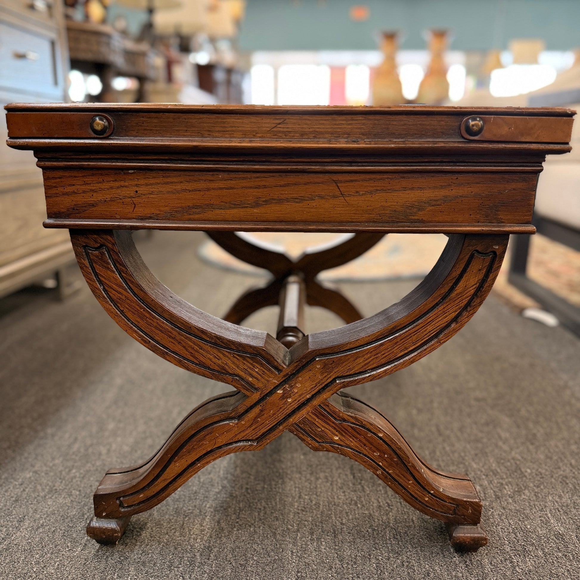 Traditional rectangular wood coffee table featuring a raised-edge tabletop, curved trestle-style legs, and decorative metal nailhead trim along the apron.