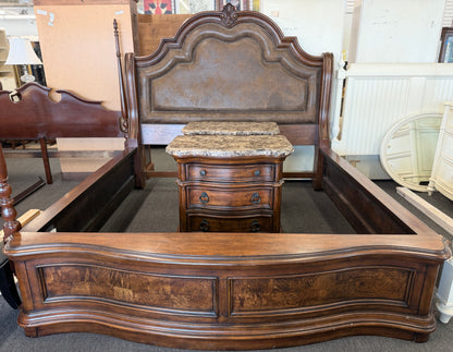 A grand wooden king bed frame flanked by two matching nightstands featuring marble tops.