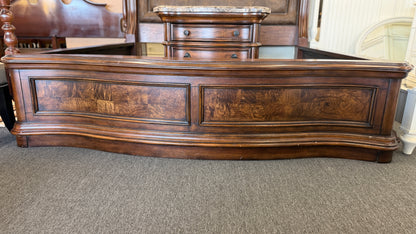 A grand wooden king bed frame flanked by two matching nightstands featuring marble tops.