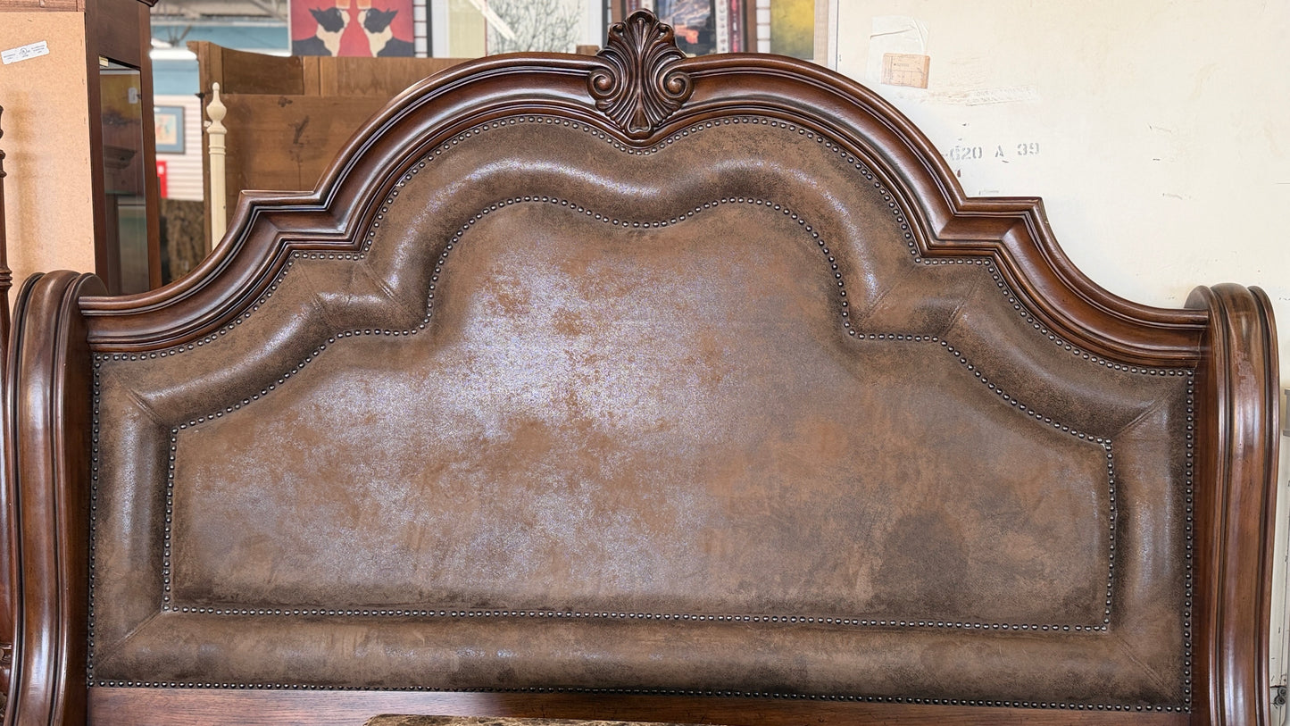 A grand wooden king bed frame flanked by two matching nightstands featuring marble tops.