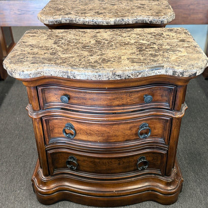 A grand wooden king bed frame flanked by two matching nightstands featuring marble tops.