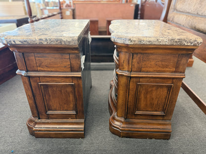 A grand wooden king bed frame flanked by two matching nightstands featuring marble tops.