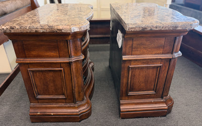 A grand wooden king bed frame flanked by two matching nightstands featuring marble tops.