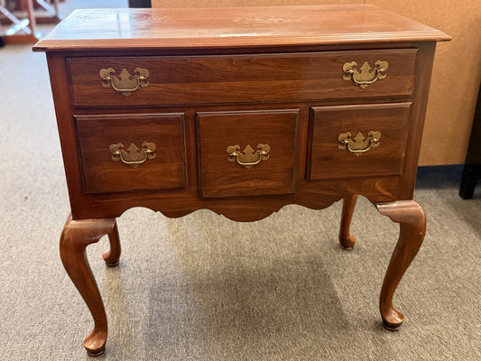 A traditional wooden lowboy accent dresser featuring four drawers with brass batwing drop pulls, a scalloped apron, and cabriole legs.