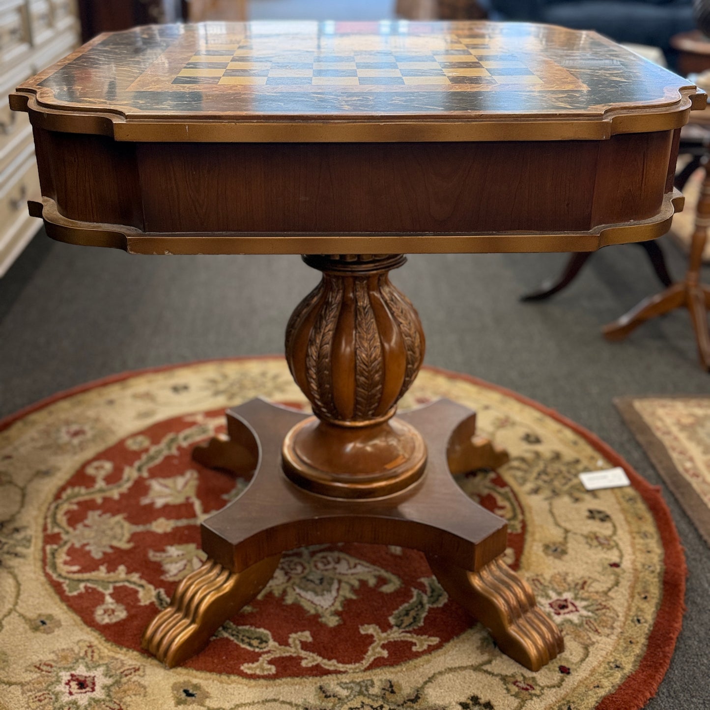 A traditional wooden pedestal chess table featuring a built-in inlaid chessboard surface, a single storage drawer with a ring pull, and a carved urn-shaped pedestal base.