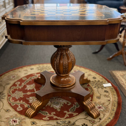 A traditional wooden pedestal chess table featuring a built-in inlaid chessboard surface, a single storage drawer with a ring pull, and a carved urn-shaped pedestal base.