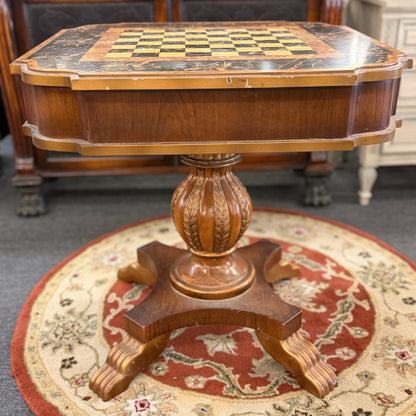 A traditional wooden pedestal chess table featuring a built-in inlaid chessboard surface, a single storage drawer with a ring pull, and a carved urn-shaped pedestal base.