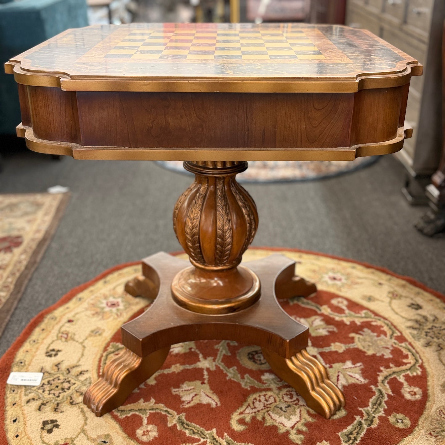 A traditional wooden pedestal chess table featuring a built-in inlaid chessboard surface, a single storage drawer with a ring pull, and a carved urn-shaped pedestal base.