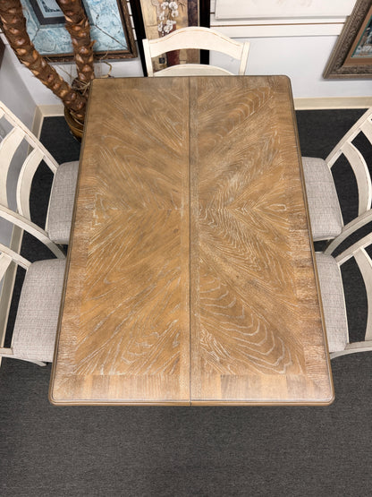 A two-tone counter-height dining set featuring a brown wood top rectangular table and six distressed white chairs with textured grey upholstered seats.