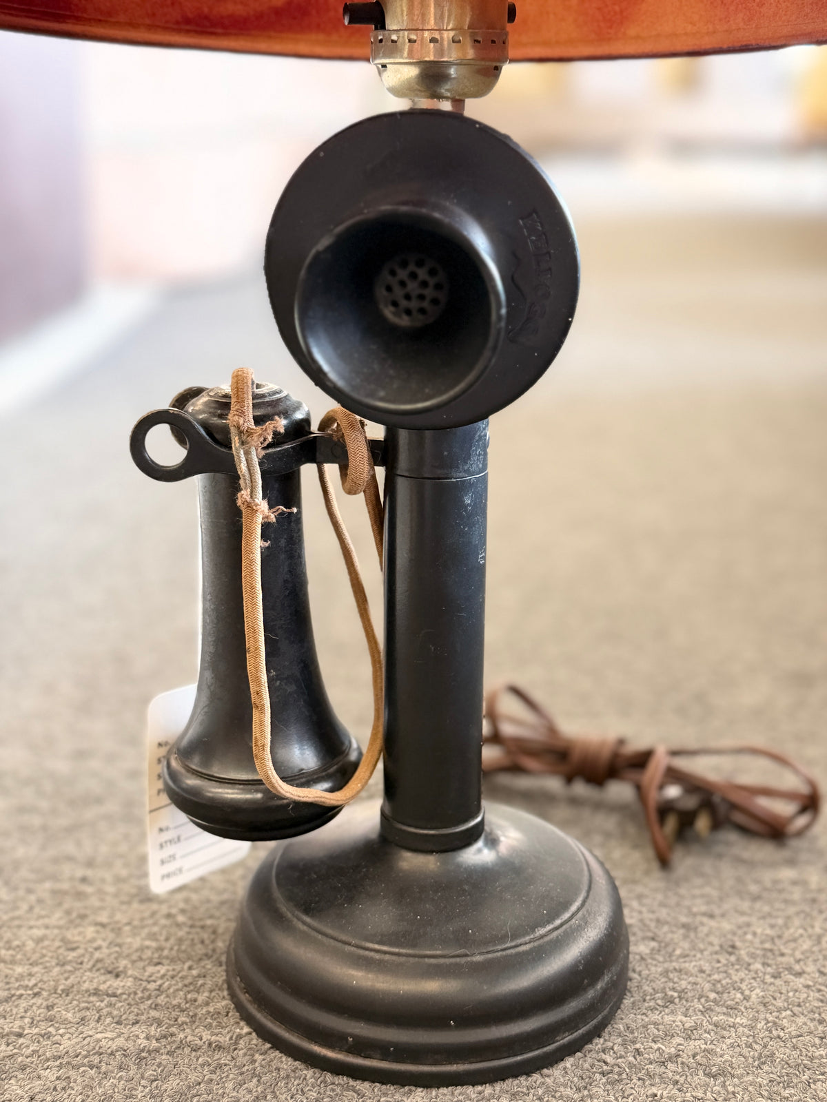 A vintage-style novelty table lamp crafted from a black candlestick telephone base with a red nautical drum shade in good condition.
