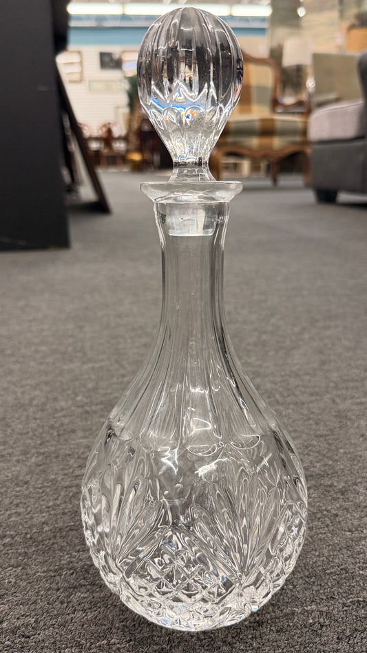 A vintage-style cut-glass decanter with crosshatch and leaf cut patterns, a tall fluted neck, and a matching faceted stopper in excellent condition.