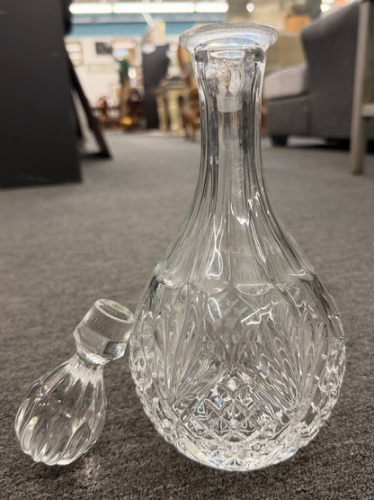 A vintage-style cut-glass decanter with crosshatch and leaf cut patterns, a tall fluted neck, and a matching faceted stopper in excellent condition.