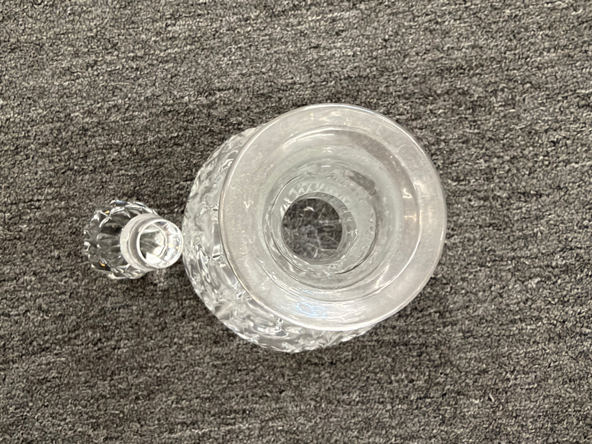 A vintage-style cut-glass decanter with crosshatch and leaf cut patterns, a tall fluted neck, and a matching faceted stopper in excellent condition.