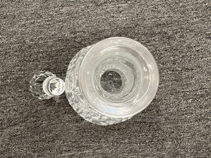 A vintage-style cut-glass decanter with crosshatch and leaf cut patterns, a tall fluted neck, and a matching faceted stopper in excellent condition.