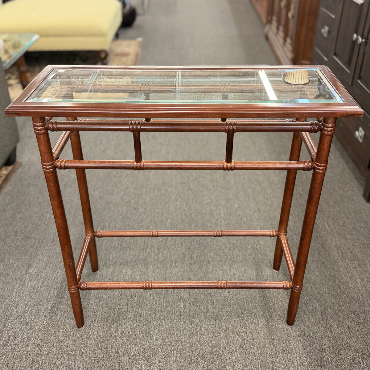 A vintage console sofa table featuring a clear glass top insert set in a faux-bamboo carved wood frame with turned stretchers in good condition.