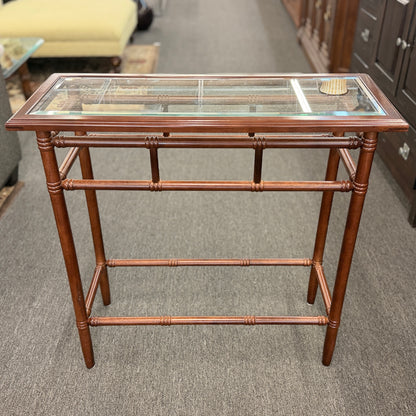 A vintage console sofa table featuring a clear glass top insert set in a faux-bamboo carved wood frame with turned stretchers in good condition.