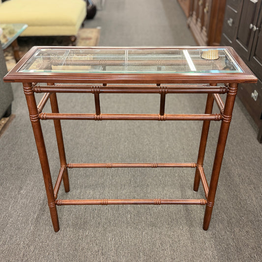 A vintage console sofa table featuring a clear glass top insert set in a faux-bamboo carved wood frame with turned stretchers in good condition.