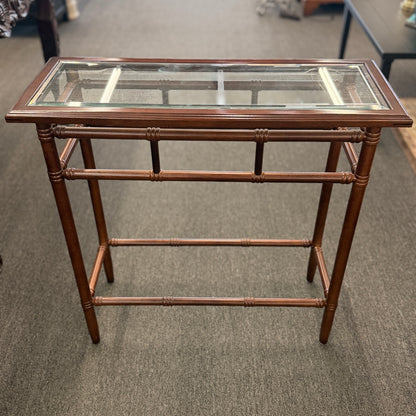 A vintage console sofa table featuring a clear glass top insert set in a faux-bamboo carved wood frame with turned stretchers in good condition.