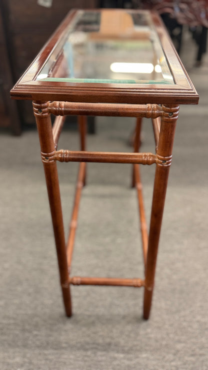 A vintage console sofa table featuring a clear glass top insert set in a faux-bamboo carved wood frame with turned stretchers in good condition.