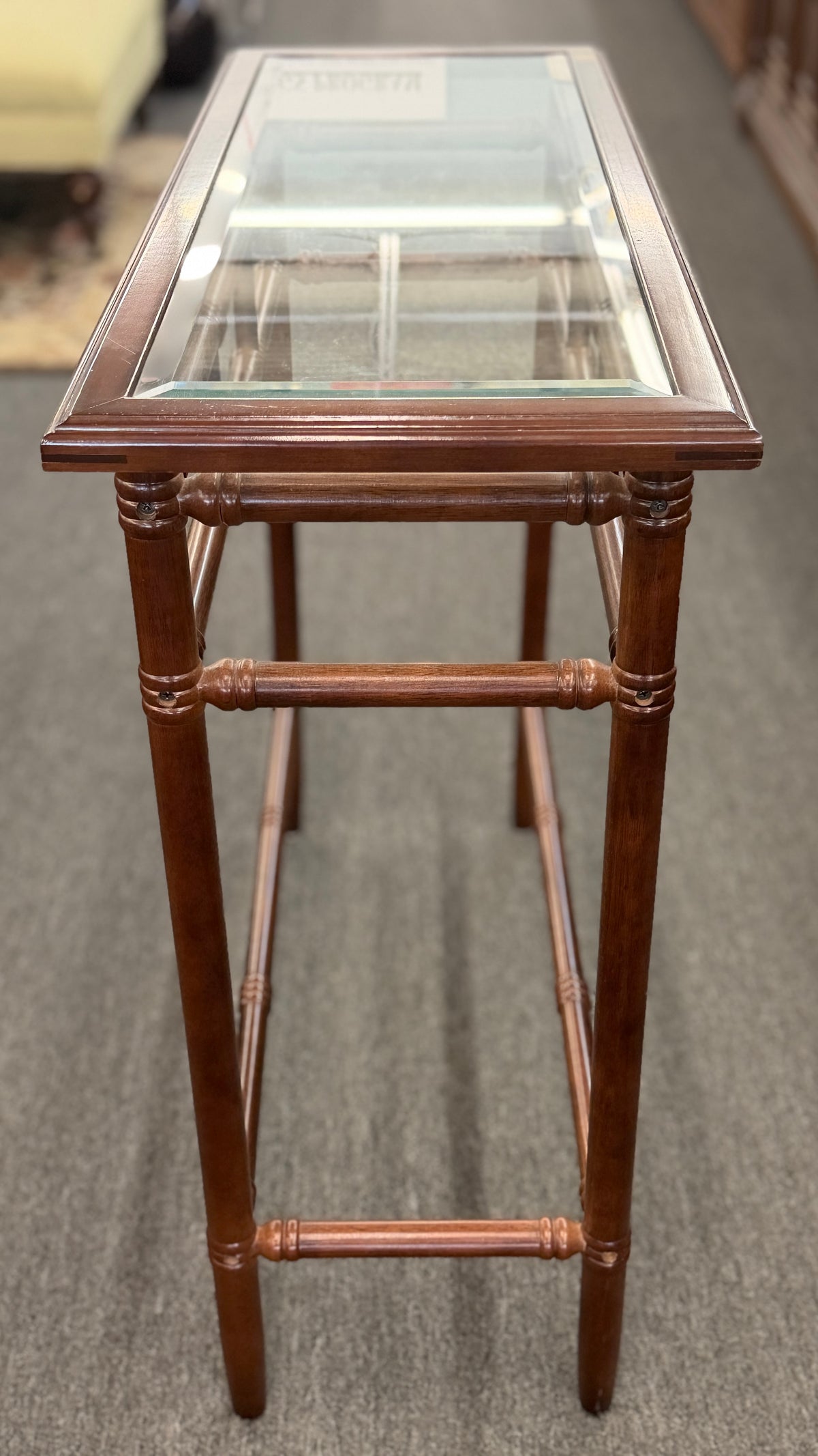 A vintage console sofa table featuring a clear glass top insert set in a faux-bamboo carved wood frame with turned stretchers in good condition.