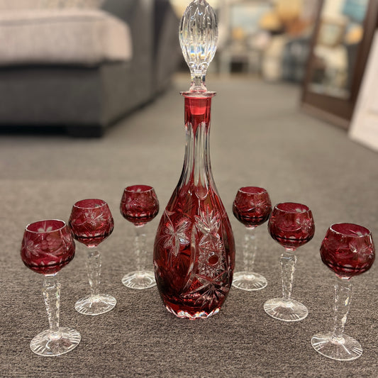 A 7-piece vintage glass barware set including a tall tapered decanter with faceted stopper and six matching stemmed cordial glasses in excellent condition.