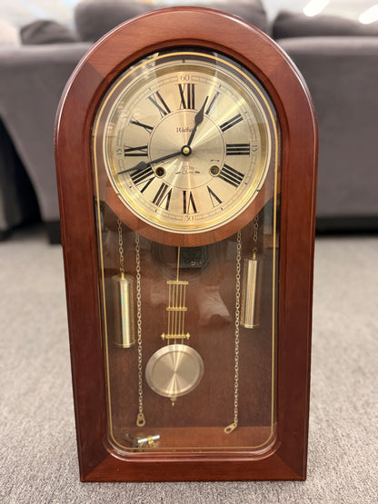 A traditional Waltham 31-day chime mantel clock in an arched cherry-finish wood case with a Roman numeral dial and brass pendulum in excellent condition.