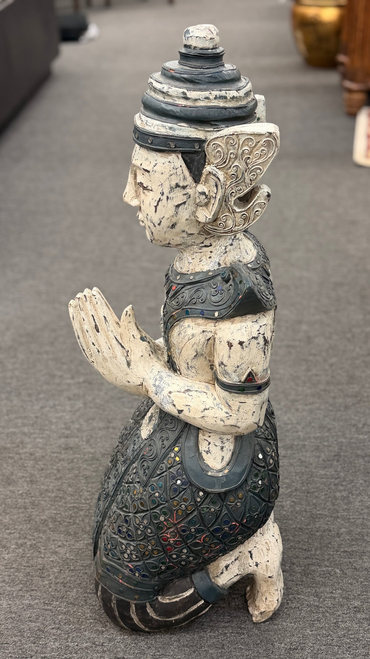 Traditional kneeling Buddhist or Southeast Asian deity statue finished in a distressed weathered white and black wash with intricate mirrored and jeweled accents in excellent condition.