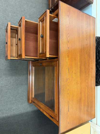 Medium-tone wood storage cabinet featuring three stacked drawers, a glass-paneled cabinet door with interior shelving, and a classic versatile design.