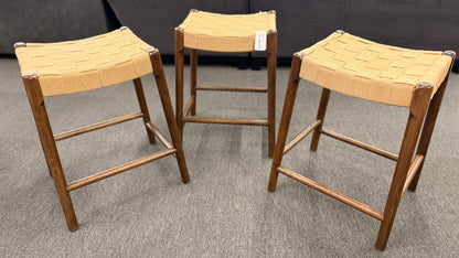 A set of three wooden backless barstools featuring woven natural-fiber seats in good condition.