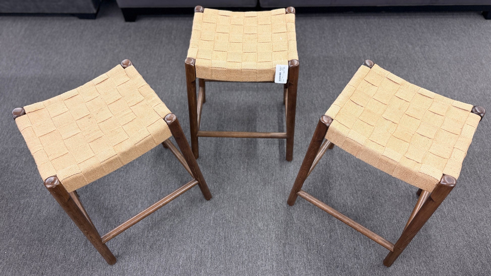 A set of three wooden backless barstools featuring woven natural-fiber seats in good condition.