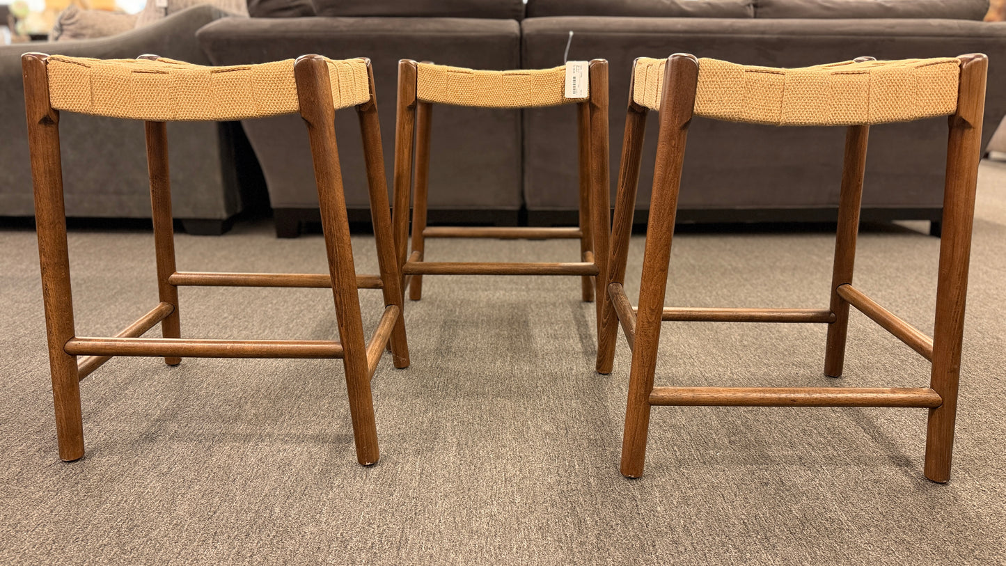 A set of three wooden backless barstools featuring woven natural-fiber seats in good condition.