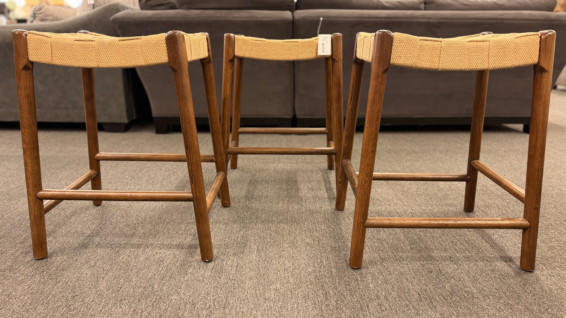 A set of three wooden backless barstools featuring woven natural-fiber seats in good condition.