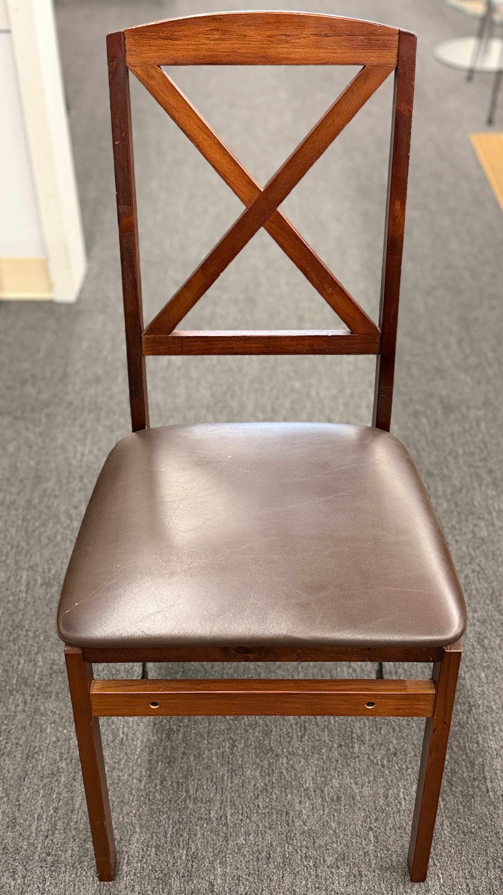 A wooden folding dining table set featuring a dark brown inset playing surface and four matching folding chairs with dark brown upholstered seat cushions.
