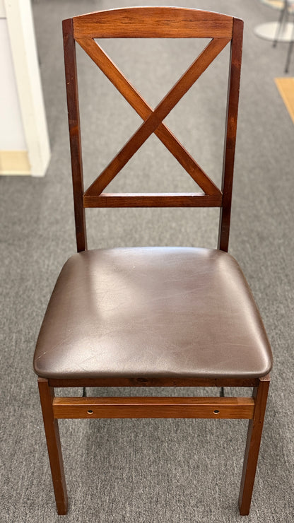 A wooden folding dining table set featuring a dark brown inset playing surface and four matching folding chairs with dark brown upholstered seat cushions.