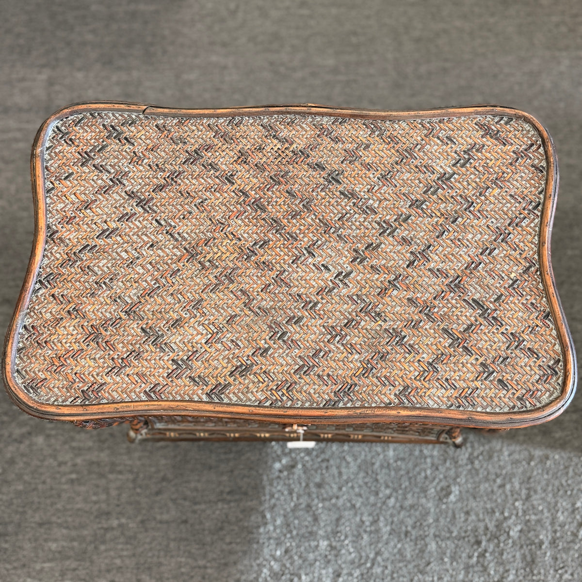 A woven rattan storage chest with a latching lid, a textured front panel, and short wooden legs in good condition.