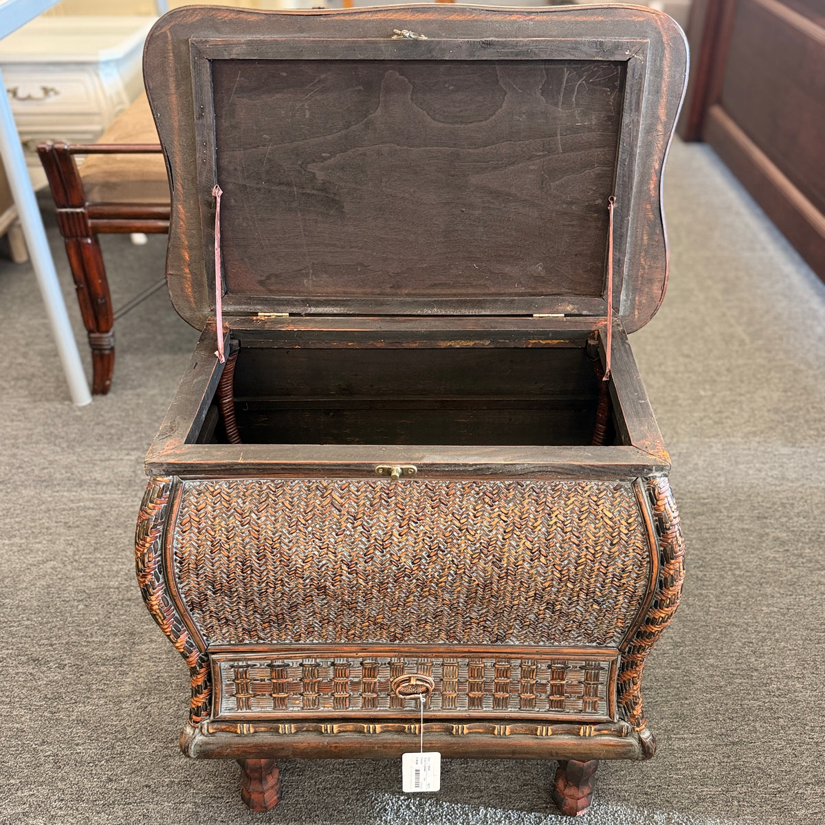 A woven rattan storage chest with a latching lid, a textured front panel, and short wooden legs in good condition.