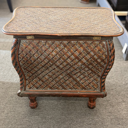 A woven rattan storage chest with a latching lid, a textured front panel, and short wooden legs in good condition.